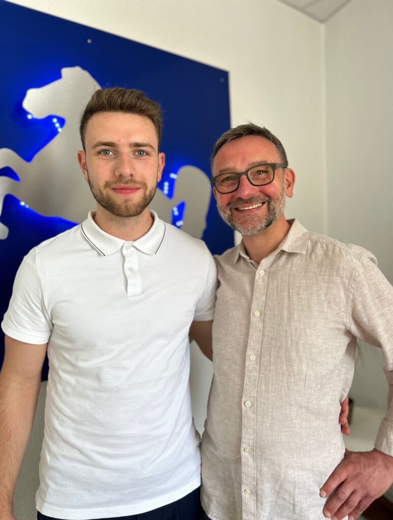 Die Gründer von Moneymatik: Foto von Michel und Kai - sie stehen Arm in Arm vor der Kamera und lächeln beide.